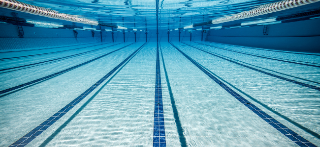 Vista subacuática de una piscina olímpica vacía con líneas marcadas en el fondo y luces en los laterales